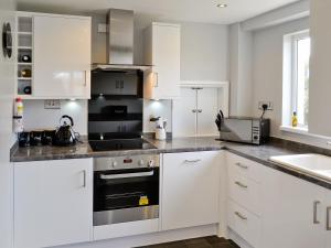 a kitchen with white cabinets and a stove top oven at Sweet Briar in Newquay