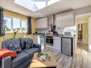 a living room with a blue couch and a kitchen at Peacock Lodge in Thurlton