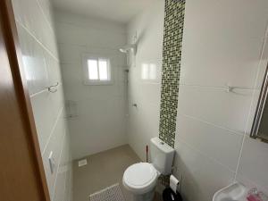 ein weißes Badezimmer mit Toilette und Dusche in der Unterkunft Casa nova para alugar no bairro zona norte in Capão da Canoa + 11 Fotos