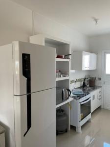 eine weiße Küche mit Kühlschrank und Herd in der Unterkunft Casa nova para alugar no bairro zona norte in Capão da Canoa