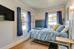 a bedroom with a bed with blue curtains and a tv at 3 Mi to Dtwn Saginaw Cozy Family Home with Yard! in Saginaw