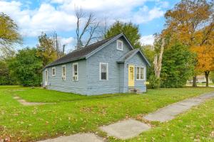 a blue house with a yellow door in a yard at 3 Mi to Dtwn Saginaw Cozy Family Home with Yard! in Saginaw