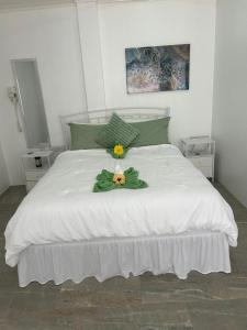 a white bed with two flowers on top of it at Agape Suites-Room 2-Ground Floor in Soufrière +5 photos