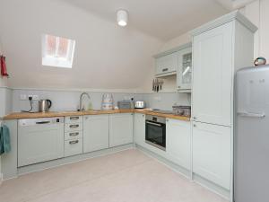 a kitchen with white cabinets and a refrigerator at Stable Yard Cottage in Selborne