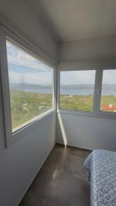 Schlafzimmer mit zwei großen Fenstern und einem Bett in der Unterkunft Chalet de montaña in Villa Carlos Paz