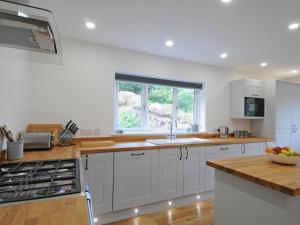 a kitchen with white cabinets and a sink and a window at Bryn Derw in Barmouth +30 photos