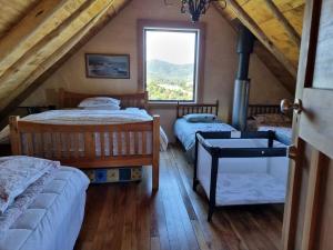 - une chambre mansardée avec 2 lits et une fenêtre dans l'établissement Pikikirunga House, Takaka Hill, à Upper Takaka