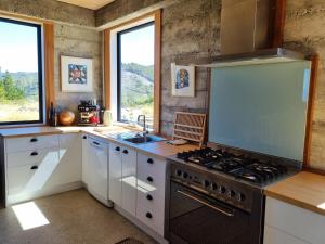 a kitchen with white cabinets and a stove top oven at Pikikirunga House, Takaka Hill in Upper Takaka