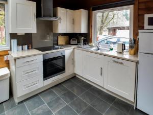 a kitchen with white cabinets and a sink at Ard Darach Lodge in Dunoon