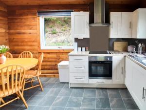 a kitchen with white cabinets and a table and a stove at Ard Darach Lodge in Dunoon +18 photos