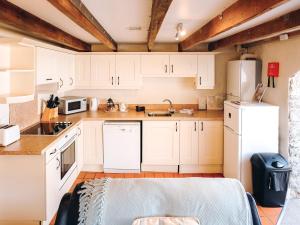 a kitchen with white cabinets and a white refrigerator at The Corn Store - Uk6716 in Lydstep