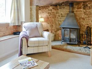 ein Wohnzimmer mit einem Stuhl und einem Herd in der Unterkunft The Old Sweet Shop in Hook Norton