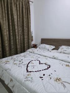a bed with a white comforter with a heart on it at غرف فندقيه - بدع زايد in Bū Rays