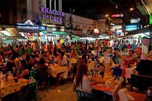 een menigte mensen die 's nachts aan tafel zitten in een straat bij GO INN Khaosan Road - โก อินน์ ตรอกข้าวสาร in Bangkok