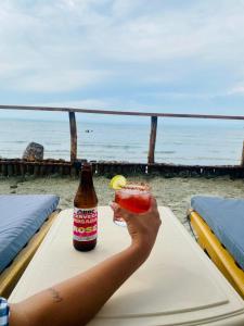 a person holding a drink with the beach in the background at Hotel Los Nogales Coveñas in Coveñas