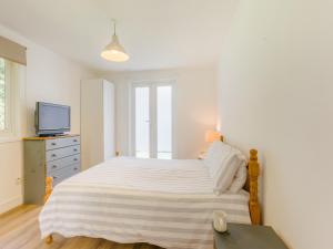 a white bedroom with a large bed and a television at Keepers Wood - W43109 in Bradworthy +14 photos