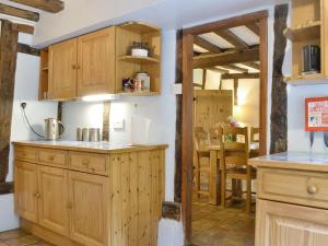 a kitchen with wooden cabinets and a dining room at Meadow Cottage in Chediston