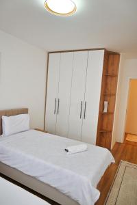 a bedroom with a bed with white sheets and white cabinets at Sweet Dreams Apartment in Pristina