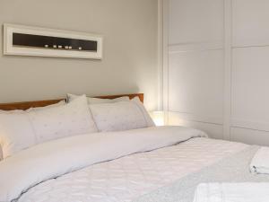 South Snowdon Wharf في بورثمادوج: غرفة نوم مع سرير أبيض وتلفزيون على الحائط +7 صور