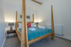 a bedroom with a large wooden bed with blue sheets at Petryal in Llangernyw