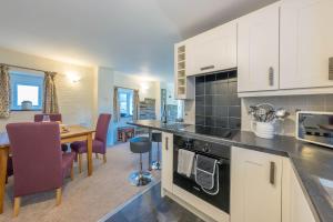 a kitchen with white cabinets and a dining room with a table at Gwyddfid-Y-Ffynnon in Llanfyrnach +17 photos