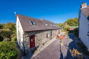 an old stone building with a red door at Gwyddfid-Y-Ffynnon in Llanfyrnach