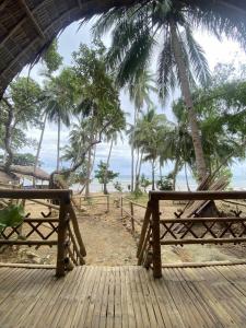 a wooden deck with palm trees and the ocean at MORE Beach in El Nido
