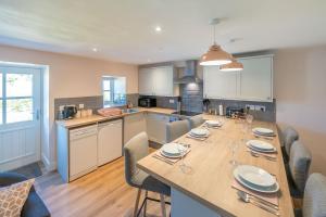 LlanerchymeddにあるBwthyn-Pili-Palaのキッチン(長い木製テーブル、椅子付)