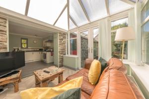 a living room with a leather couch and a tv at Eiddew-Y-Ffynnon in Llanfyrnach