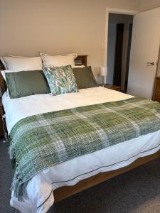a bed with a green and white blanket on it at Raynbird Cottage in Dunedin +7 photos