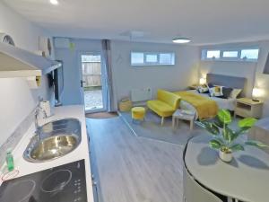 a kitchen and a living room with a yellow couch at The Secret Luxury Apartment in New Romney +14 photos