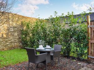 a table and chairs in a garden with a hedge at Uk45886 - The Studio At Cross House in Kirkby Lonsdale