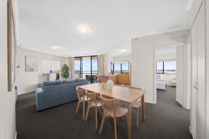 Una sala de estar con una mesa y un sofá azul. en Seaside Solace at Caloundra Seaview 3BD Apartment, en Caloundra