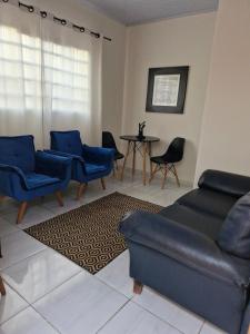a living room with blue chairs and a couch and a table at House - Cantinho de Jacaré in Jacarèzinho