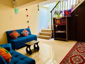 a living room with a blue couch and a staircase at ECOTERRA-SAN FRANCISCO Cusco in Cusco