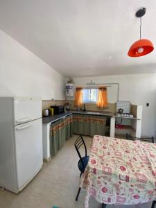 a kitchen with a table and a white refrigerator at Caminito in Villa Anizacate