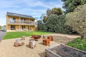 a house with a yard with a garden with logs at Sunnys Beachhouse - 70 Hargreaves Rd, Middleton in Middleton