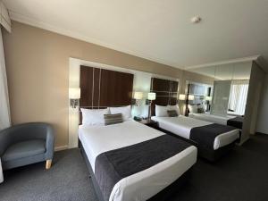 een hotelkamer met twee bedden en een stoel bij Mantra on View in Gold Coast