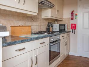 a kitchen with white cabinets and a stove top oven at Gatekeepers Cottage Uk6728 in Lydstep