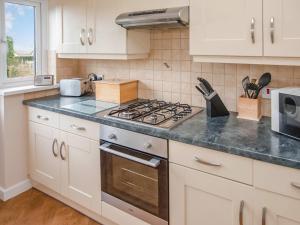 a kitchen with white cabinets and a stove top oven at Gatekeepers Cottage Uk6728 in Lydstep