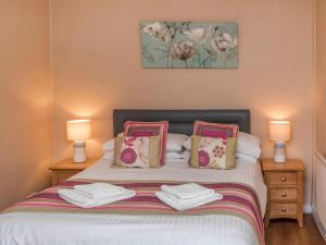 a bedroom with a bed with two lamps and towels at Gatekeepers Cottage Uk6728 in Lydstep