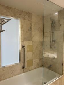 een douche met een glazen deur en een bad bij Mantra on View in Gold Coast