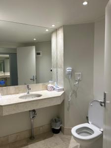 een badkamer met een toilet, een wastafel en een spiegel bij Mantra on View in Gold Coast