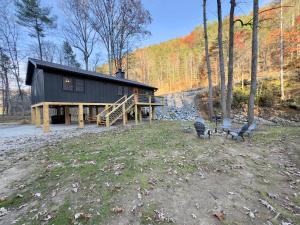 a black house with a porch and chairs in front of it at Cozy Creekside cabin- 35m to Boone in Butler