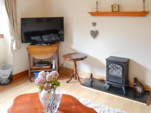 a living room with a fireplace and a television at Seashell Cottage in Nairn