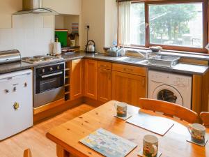 a kitchen with a table and a stove and a dishwasher at Seashell Cottage in Nairn