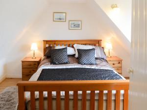 a bedroom with a wooden bed with two lamps at Seashell Cottage in Nairn