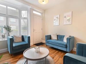 a living room with two blue chairs and a table at Beaconsfield House in Mundesley
