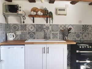 a kitchen with white cabinets and a sink at Three Ash Cottage in Bungay