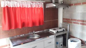 a kitchen with a sink and a red curtain at Mini Complejo Familiar Roque in Mina Clavero
